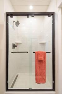 La salle de bains est pourvue d'une douche en verre avec une serviette orange. dans l'établissement New Southwest Shipping Container-In Alpine, à Alpine