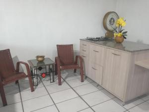 een keuken met 2 stoelen en een tafel met een klok bij Rhostel Boqueirão in Passo Fundo