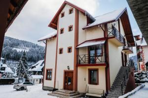 una casa en la nieve con un patio cubierto de nieve en Melody Hotel, en Bukovel