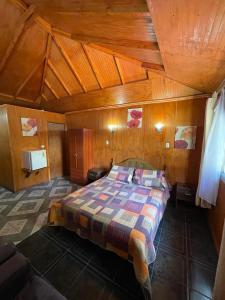 ein Schlafzimmer mit einem Bett in einem Holzzimmer in der Unterkunft Cabañas Los Olmos in San José de Maipo