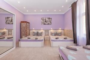 2 camas en una habitación con paredes moradas en Queen Apartments, en Cracovia