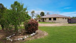 a house with a bush in front of a yard at Hans Christian - A family acreage escape in Sarina