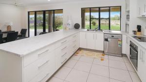 a kitchen with white cabinets and a counter top at Hans Christian - A family acreage escape in Sarina