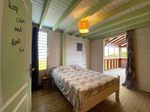 a bedroom with a bed in a room with a porch at Villa Atypique - Charme & Confort in Le Moule