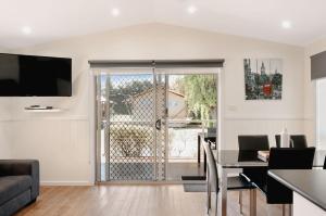 sala de estar con mesa de comedor y puerta corredera de cristal en Port Fairy Holiday Park, en Port Fairy