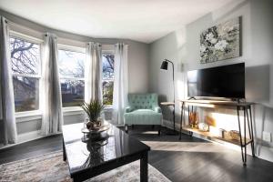 uma sala de estar com uma televisão, uma cadeira e janelas em Elegant 1BR 1 Bath apartment minutes the falls em Niagara Falls