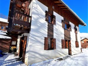 biały budynek z drewnianymi oknami na śniegu w obiekcie Appartement cosy aux Sybelles, grand extérieur, garage privé, proche pistes, parfait pour familles - FR-1-267-246 w mieście Villarembert +9 zdjęć