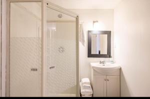 ein weißes Bad mit einer Dusche und einem Waschbecken in der Unterkunft Triple K Cozy Private Suite in Portland Estate in Halifax