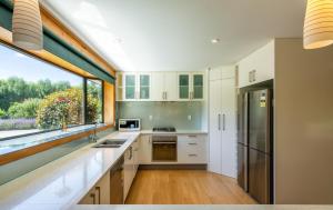 eine Küche mit weißen Schränken und einem großen Fenster in der Unterkunft Miranda Farm - Away from city, surrounded by animals in Kaiapoi
