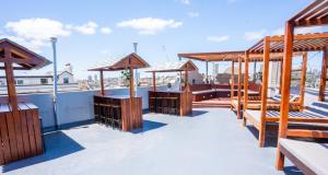 una terraza en la azotea con bancos y sombrillas de madera en Mad Monkey Bayswater, en Sídney
