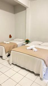 2 Betten in einem Zimmer mit weißen Wänden in der Unterkunft SÃO CRISTOVÃO HOTEL in São Luís