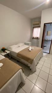 um quarto com 2 camas e piso em azulejo em SÃO CRISTOVÃO HOTEL em São Luís