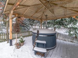 uma banheira de hidromassagem sob um gazebo de madeira na neve em Charming house with sauna and Nordic bath em Bullange