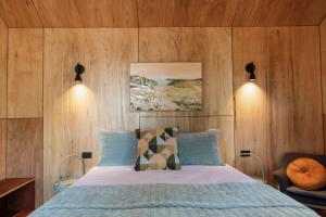 1 dormitorio con 1 cama con paredes de madera en Bicheno Garden Cottages en Bicheno