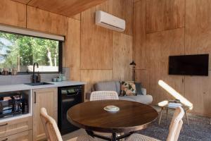 una cocina y una sala de estar con una mesa en una casa pequeña en Bicheno Garden Cottages en Bicheno