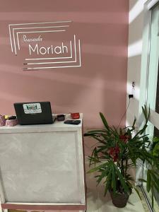 a desk with a laptop on a pink wall at Pousada Moriah 700 metrôs Magic City in Suzano