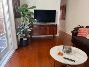 een woonkamer met een flatscreen-tv en een tafel bij Lovely Victorian Terrace - Entire home in Melbourne