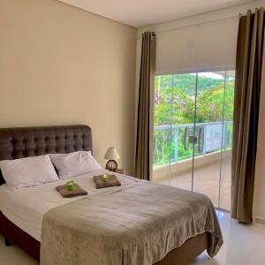a bedroom with a large bed and a large window at Pousada Moriah 700 metrôs Magic City in Suzano