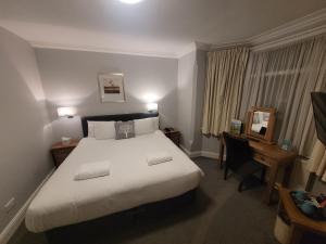 a hotel room with a large bed and a desk at The Beeches Hotel & Leisure Club in Nottingham