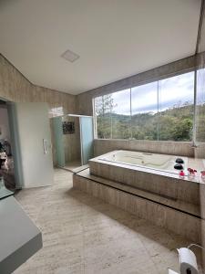 een grote badkamer met een bad en een groot raam bij Pousada Moriah 700 metrôs Magic City in Suzano