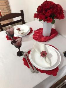 a table with two plates and a vase of red roses at Pousada Moriah 700 metrôs Magic City in Suzano