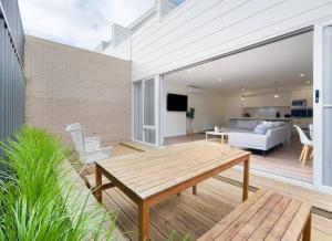 a patio with a wooden table and a living room at Schnapper Lane in Warrnambool