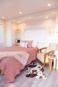 1 dormitorio con cama, silla y alfombra de perro en New Cowgirl Shipping Container Home, en Alpine