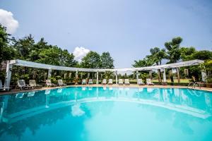 einen Pool in einem Resort mit Stühlen und Bäumen in der Unterkunft The Legacy River Kwai Resort in Kanchanaburi