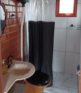ein Bad mit einem schwarzen Duschvorhang und einem WC in der Unterkunft Chalé Tribos Livres in Torres