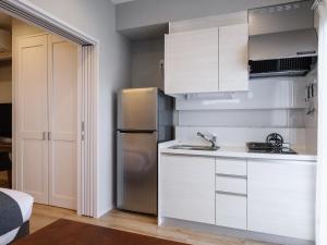 La cuisine est équipée de placards blancs et d'un réfrigérateur en acier inoxydable. dans l'établissement Family Condo Chatan Hills by Coldio Premium, à Chatan
