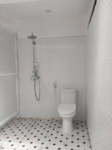 a white bathroom with a shower and a toilet at Ananda Resort Seminyak in Seminyak