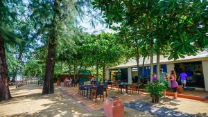 a group of people sitting at tables under trees at Baan Khaolak Beach Resort in Khao Lak