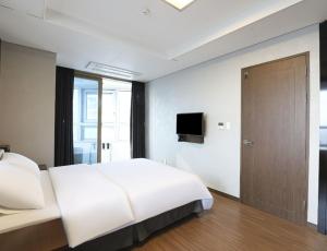 um quarto com uma grande cama branca e uma porta em Haeundae Wide Ocean VIEW em Busan