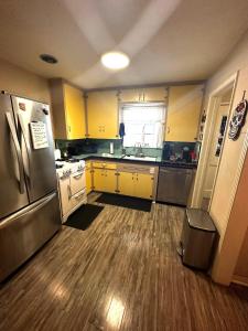 a kitchen with yellow cabinets and a stainless steel refrigerator at Charming 2 Bed Mid-City Living only 7 Min to Downtown in Tucson