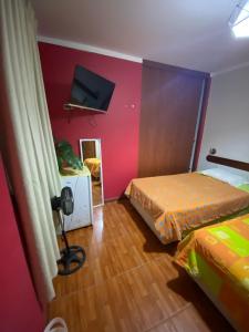 1 dormitorio con 2 camas y TV en la pared en Hostal Pacasmayo Beach, en Pacasmayo