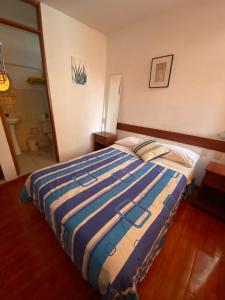 een slaapkamer met een bed met een blauw en wit gestreepte deken bij Hostal Pacasmayo Beach in Pacasmayo