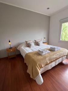 a white bedroom with a large bed and a window at Casa Los Olivos in Nueve de Julio