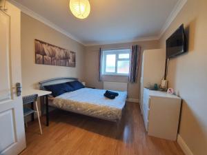 a bedroom with a bed and a desk and a window at Ilford Rooms in Goodmayes