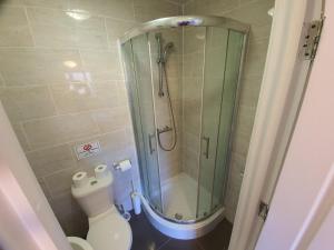 a bathroom with a shower and a toilet in it at Ilford Rooms in Goodmayes