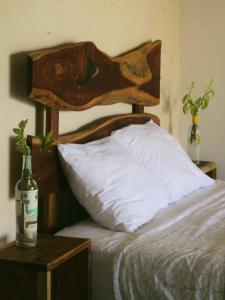 Una cama con cabecero de madera y una botella de vino. en Tropic Bacalar en Bacalar