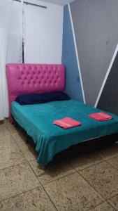 a bed in a room with a pink and blue bedvisor at Hostel Bimba Goiânia - Unidade 04 in Goiânia