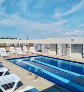 a swimming pool with lounge chairs next to a building at Apartamento Flat Palladium in São Vicente