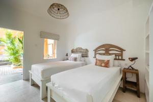two beds in a white room with a window at The Room Padang-Padang in Uluwatu