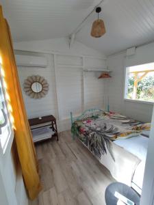 a bedroom with a bed in a room with a window at Bungalow Soleil Levant in Le Robert