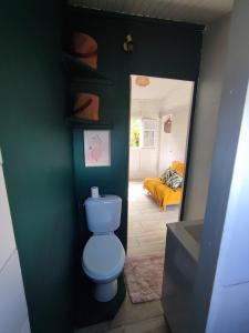 a bathroom with a blue toilet and a bedroom at Bungalow Soleil Levant in Le Robert