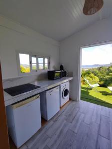 a kitchen with white appliances and a large window at Bungalow Soleil Levant in Le Robert