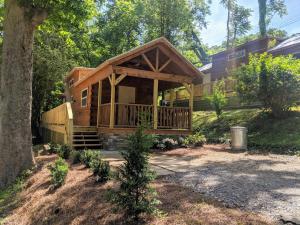 uma cabana de madeira na floresta com um alpendre em Ani Cabin Tiny Home Bordered By National Forest em Chattanooga