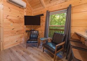 a dining room with two chairs and a television in a log cabin at Celina Cabin Nature Cabin Near Downtown Chattanooga in Chattanooga