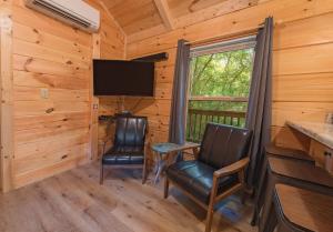 ein Esszimmer mit 2 Stühlen und einem TV in einem Blockhaus in der Unterkunft Celina Cabin Nature Cabin Near Downtown Chattanooga in Chattanooga