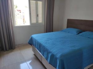a bedroom with a blue bed with a window at Casa na praia p aproveitar com a família e amigos in Capão da Canoa